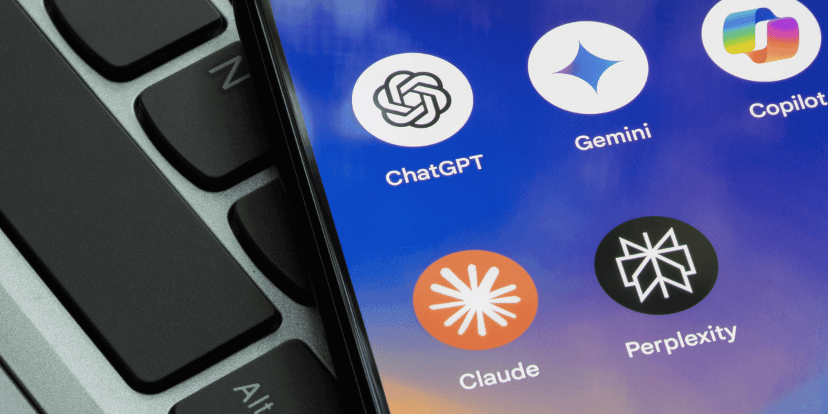Smartphone screen displaying popular AI chatbot applications including ChatGPT, Gemini, Claude, Copilot, Perplexity AI, and Summon Worlds, placed on a laptop keyboard.