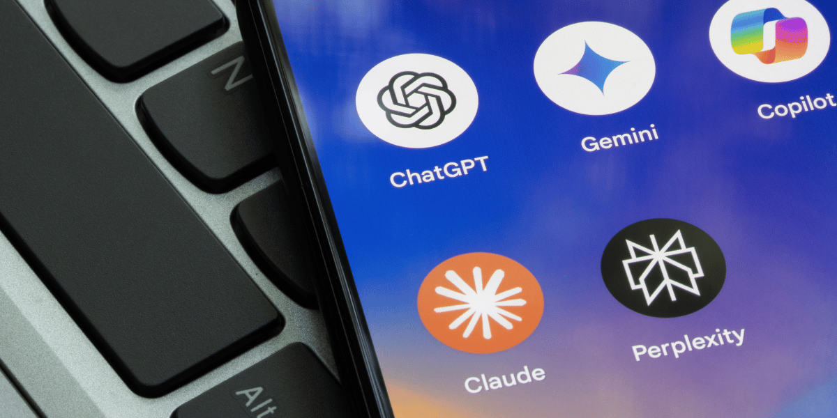 Smartphone screen displaying popular AI chatbot applications including ChatGPT, Gemini, Claude, Copilot, Perplexity AI, and Summon Worlds, placed on a laptop keyboard.